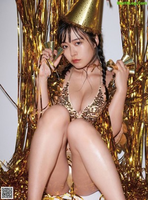A woman in a gold outfit sitting on a chair.