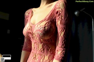 A woman in a pink dress standing in front of a mirror.