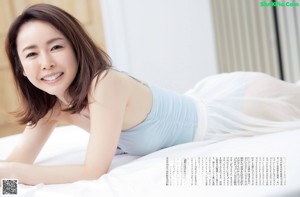 A woman laying on a bed smiling at the camera.