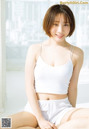 A woman in a white tank top and shorts laying on the floor.