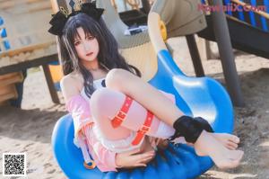A woman in a white bikini sitting on a playground.