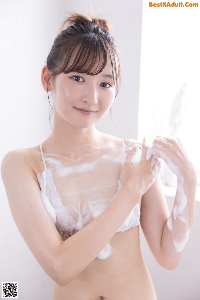 A woman is washing her body with foam. 