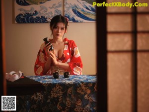 A woman in a red kimono sitting on a chair.