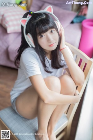 A woman holding a pink and white checkered pillow and wearing headphones.