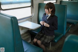 A woman in a school uniform is standing on a train.