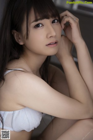 A woman in a white lingerie holding a spoon in her mouth.
