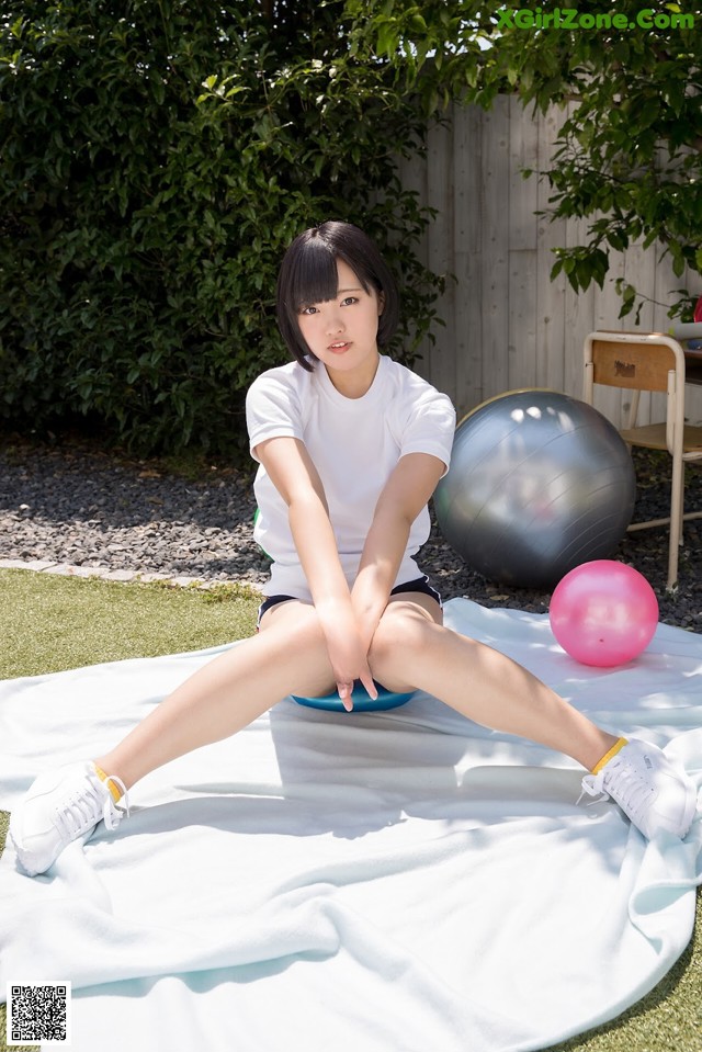 A woman sitting on a blanket next to a pink ball.
