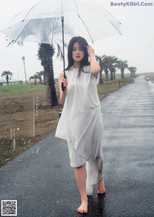 A woman sitting on the ground in front of a white wall.