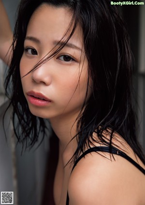 A woman in a black bathing suit sitting on a brick walkway.