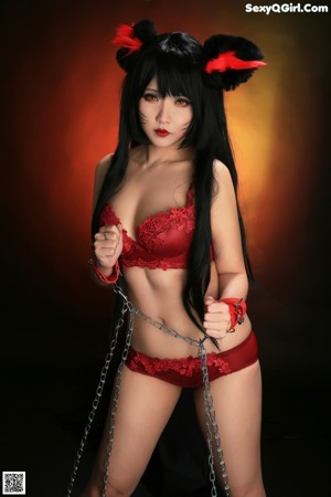 A woman in a red and black outfit is tied up with chains.