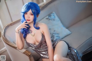 A woman with blue hair sitting on a green chair.