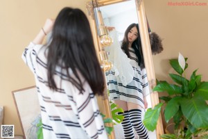 A woman standing in front of a mirror in a bedroom.