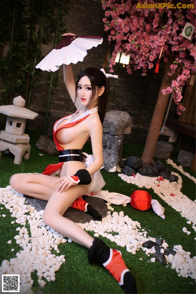 A woman in a red and white outfit holding a fan.