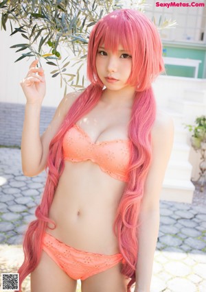 A woman in a pink bikini sitting on a bed.