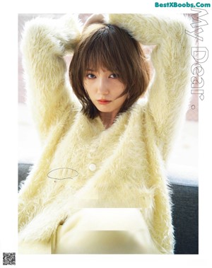 A woman in a white hoodie and green pants posing for a magazine.