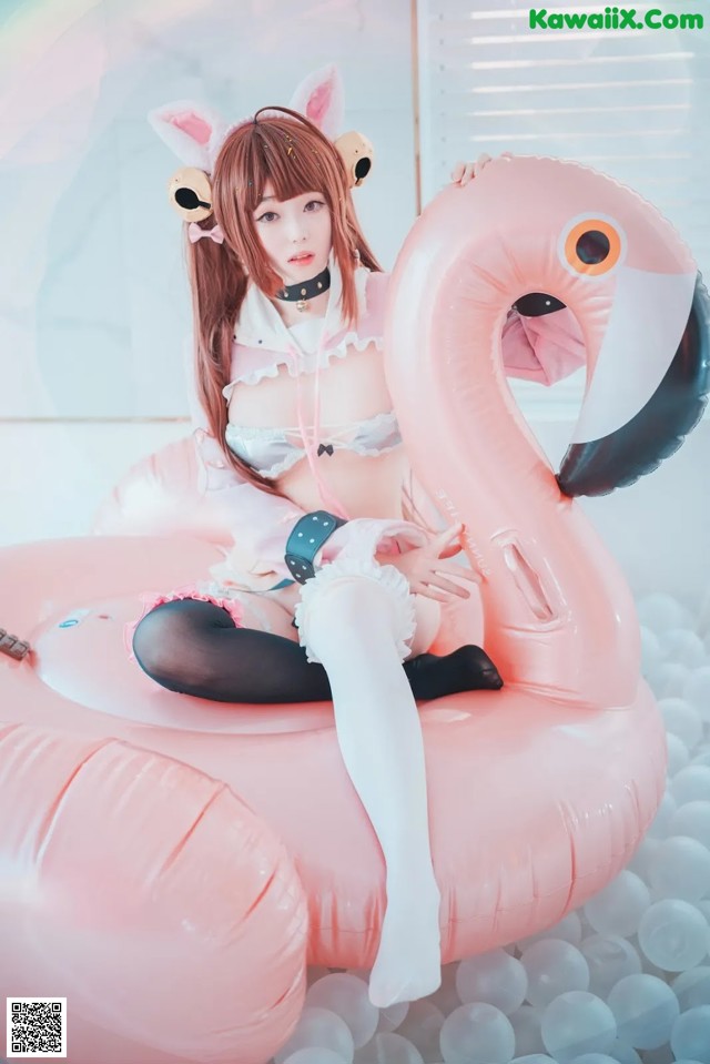 A woman sitting on top of an inflatable flamingo.