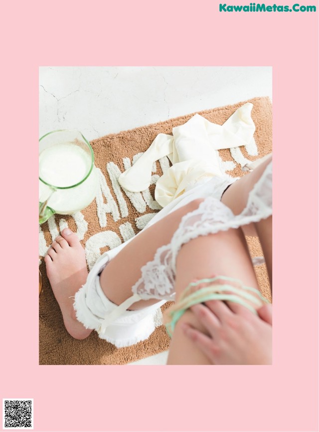 A woman in white lingerie sitting on a rug next to a glass of milk.