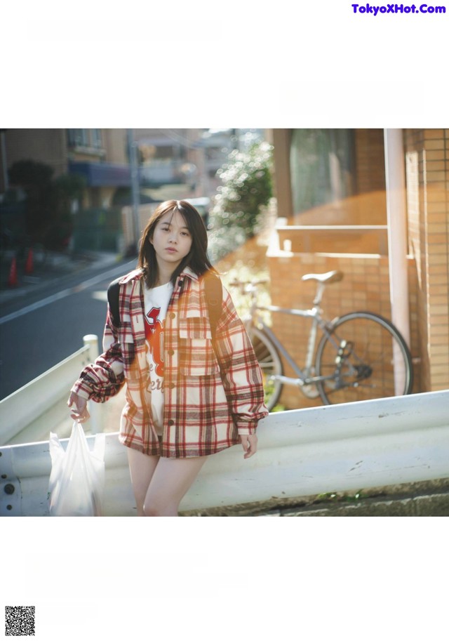 A woman in a plaid shirt is walking down the street.