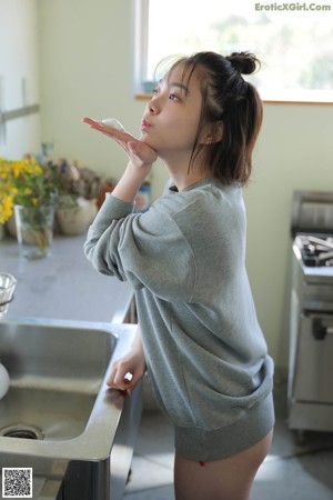 A woman in a gray sweatshirt holding a book over her head.