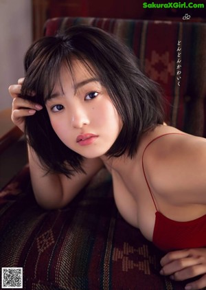 A woman in a white bra sitting on a wooden chair.