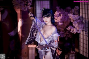A woman in a kimono holding a samurai sword.