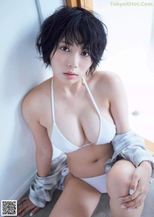 A naked asian woman leaning against a wall.