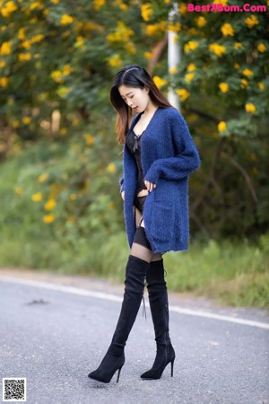 A woman in a blue cardigan and black lingerie posing for a picture.