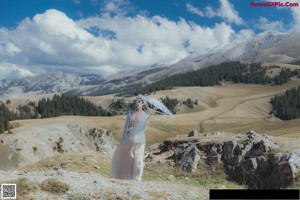 A woman in a white dress standing on a wooden bridge.
