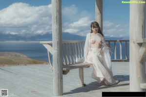 A woman standing on top of a mountain next to the ocean.
