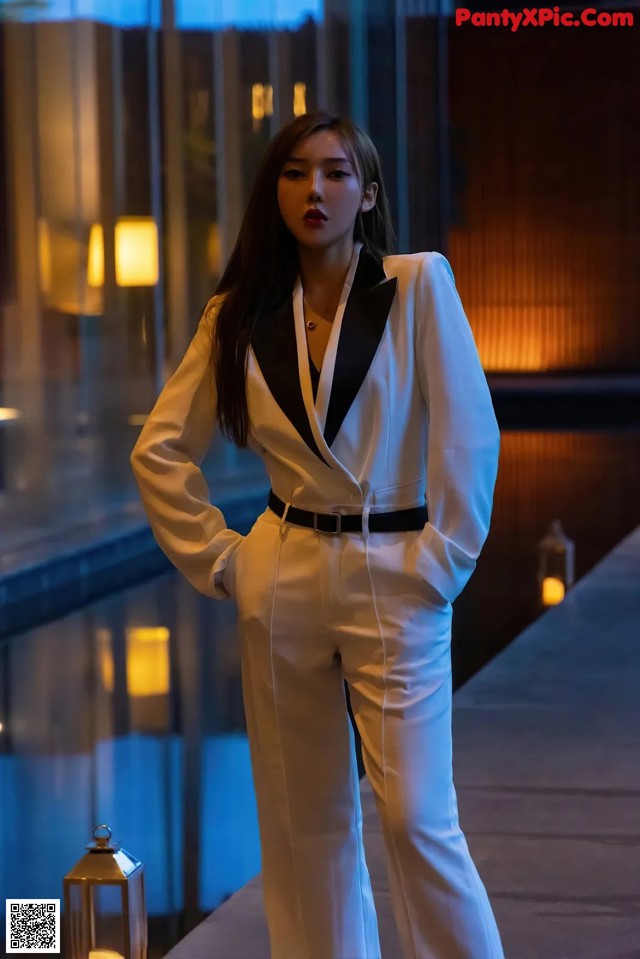 A woman in a white suit standing next to a pool.