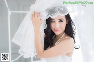 A woman in a white lingerie sitting on a bed.