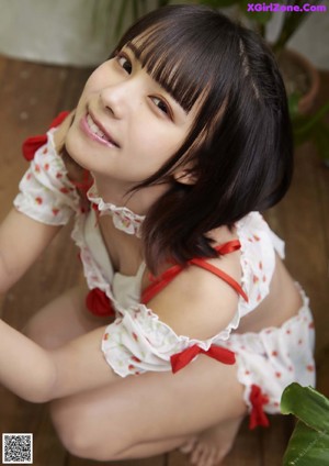 A woman in a white and red dress sitting on a chair.