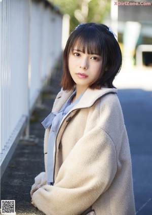 A woman in a beige coat posing for a picture.