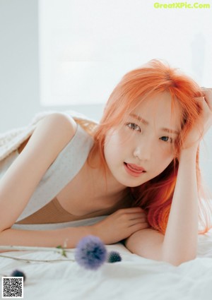 A woman with long red hair sitting on a couch.